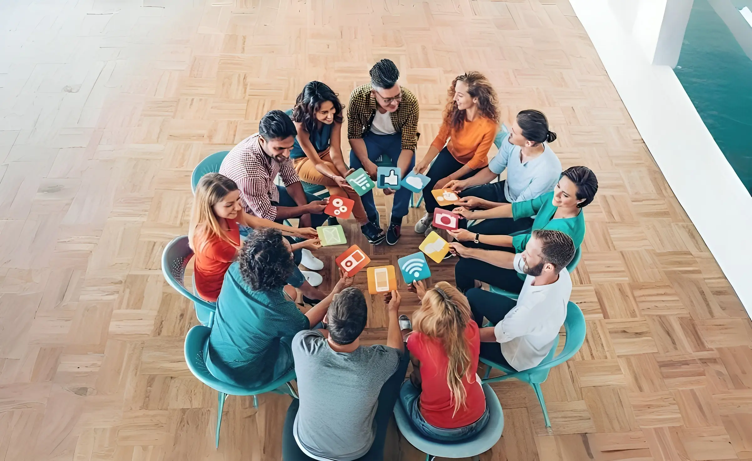 Diverse group of professionals sitting in a circle on a wooden floor, discussing and holding cards with social media icons.