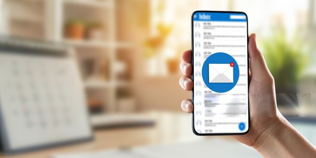 Hand holding a smartphone displaying an email inbox with a new message notification, symbolizing digital communication or sms marketing.