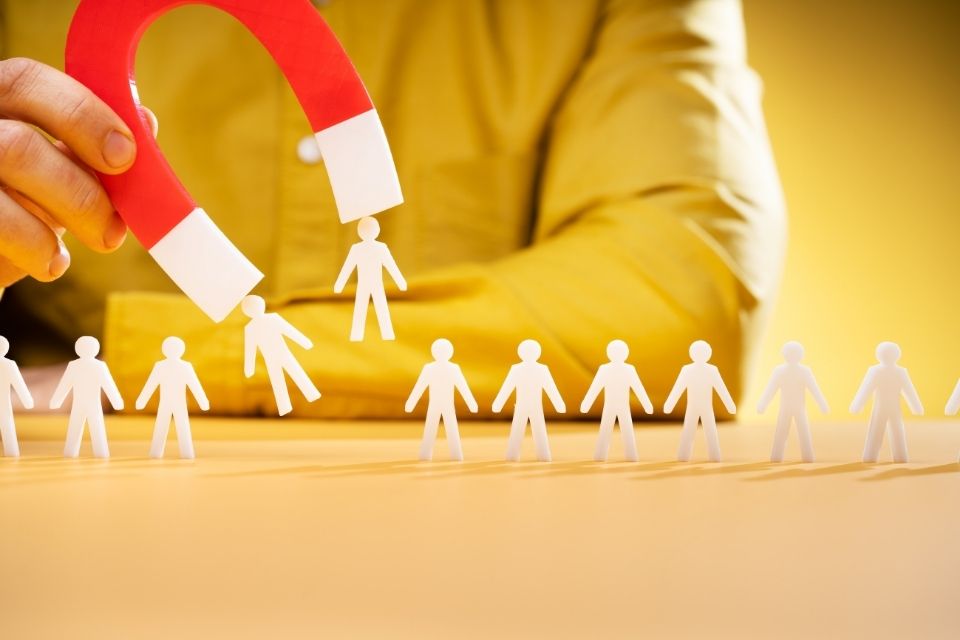 A red and white magnet attracting paper cut-out figures