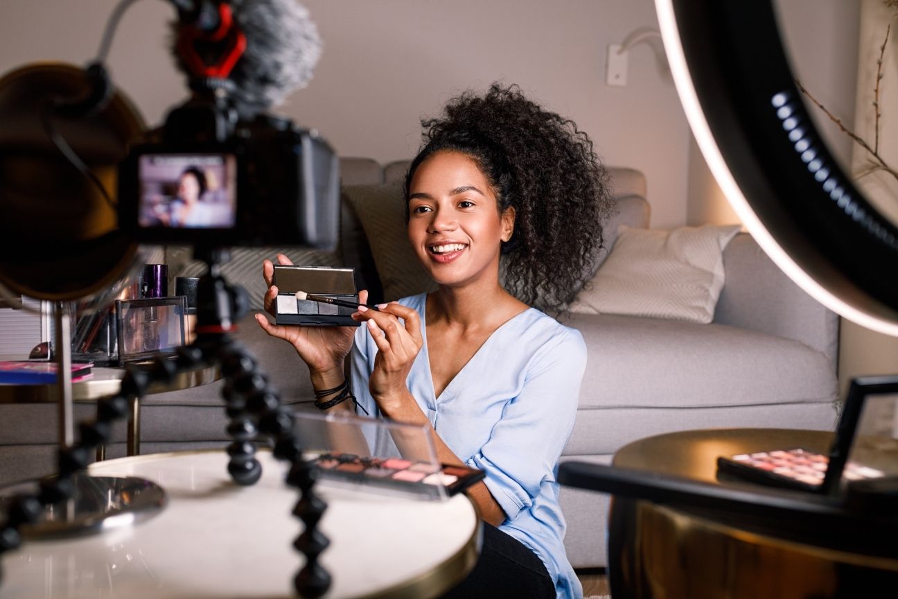 Female content creator filming a product review with camera and ring light, representing influencer marketing and video content strategy