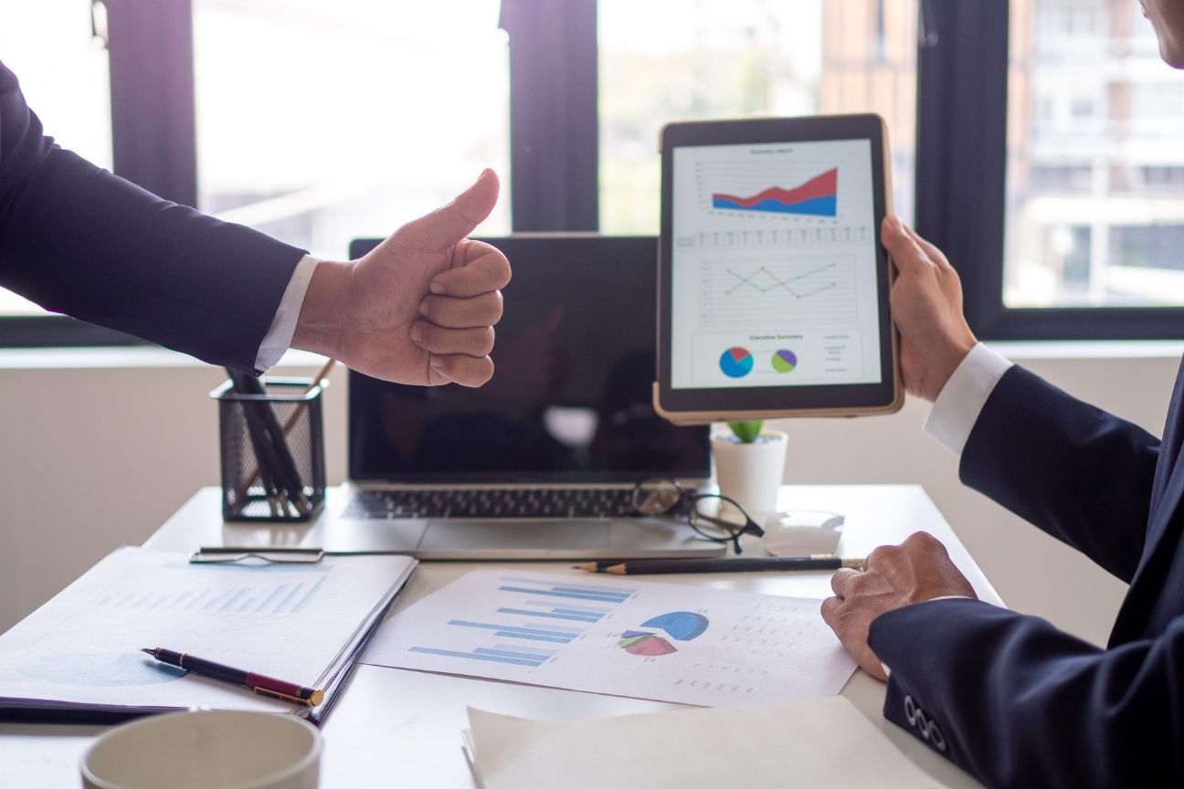 Business team reviewing conversion growth on a tablet with a thumbs-up, indicating successful CRO results.