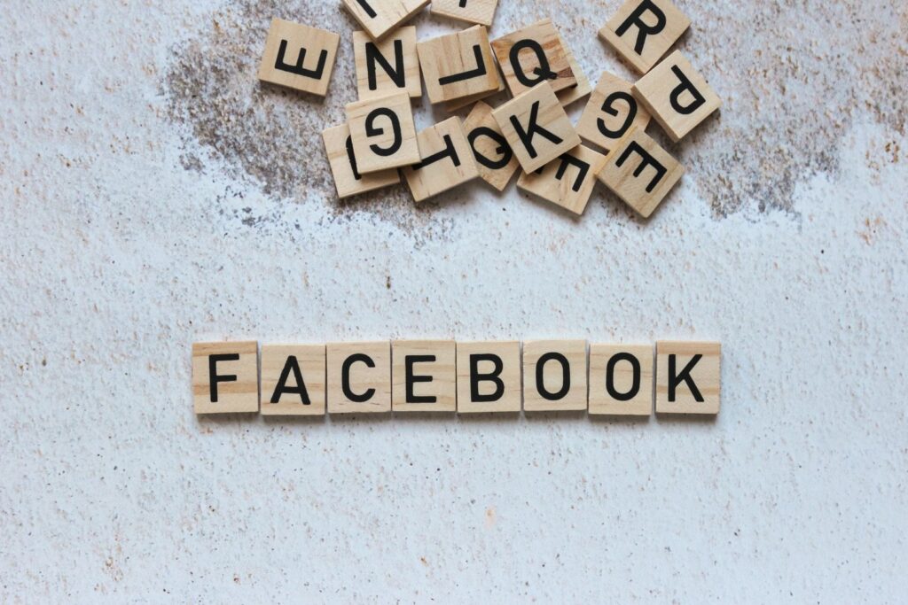 The word 'FACEBOOK' spelled out with wooden letter tiles on a textured background