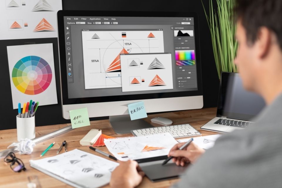 A graphic designer working on a computer, creating a logo design with a graphics tablet