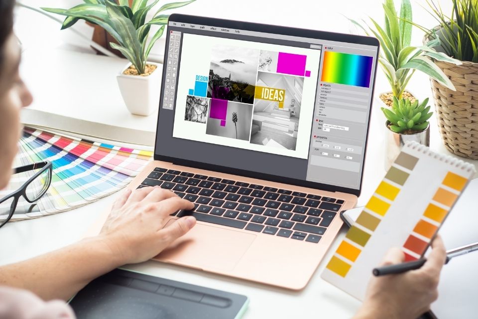A graphic designer working on a laptop, using design software to create a visual composition with images, text, and color palettes.
