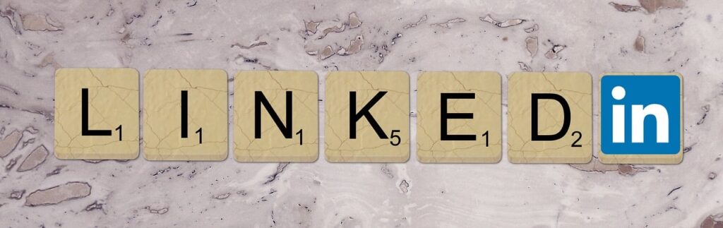 LinkedIn spelled out using Scrabble-style letter tiles on a marble background, with the official LinkedIn logo for 'in