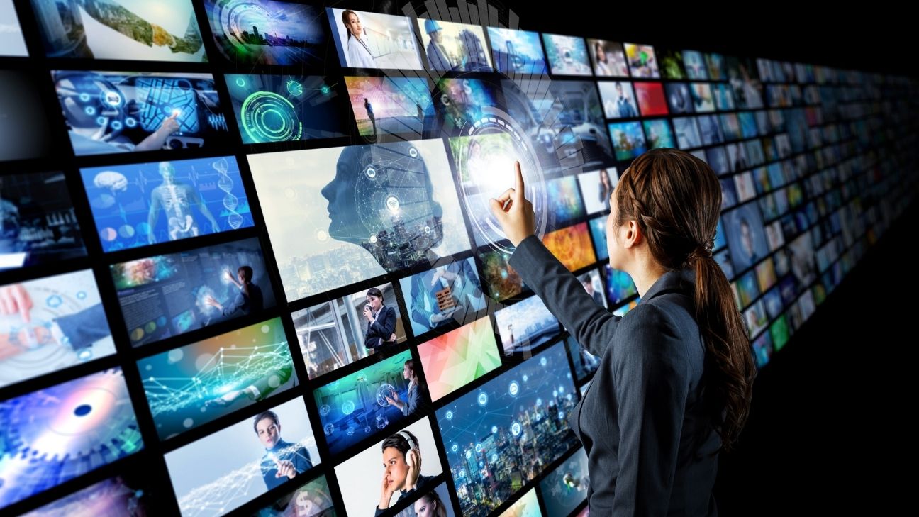 WUganda interacting with a large digital wall displaying multiple video screens, symbolizing video content selection and digital marketing technology.
