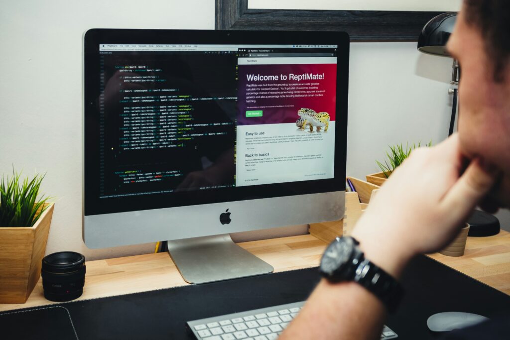 Web developer reviewing code and website layout on a desktop screen during PHP web development.