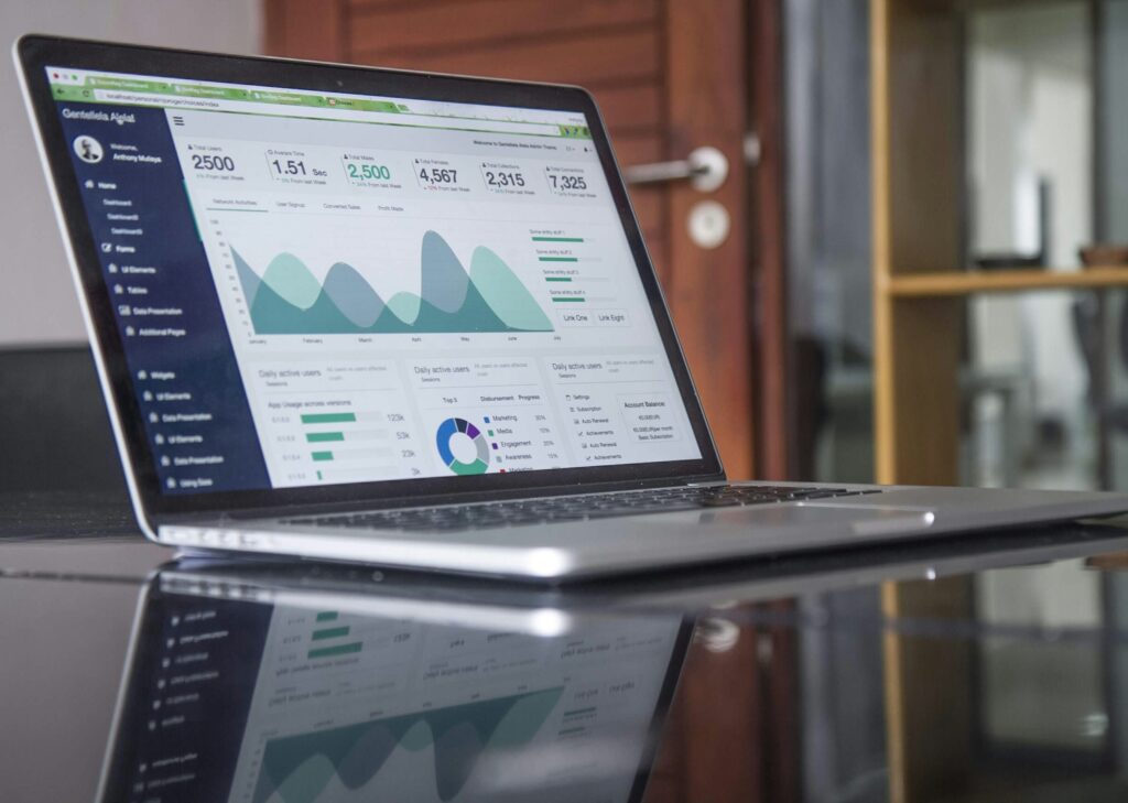A laptop on a desk displaying a web analytics dashboard with graphs and data