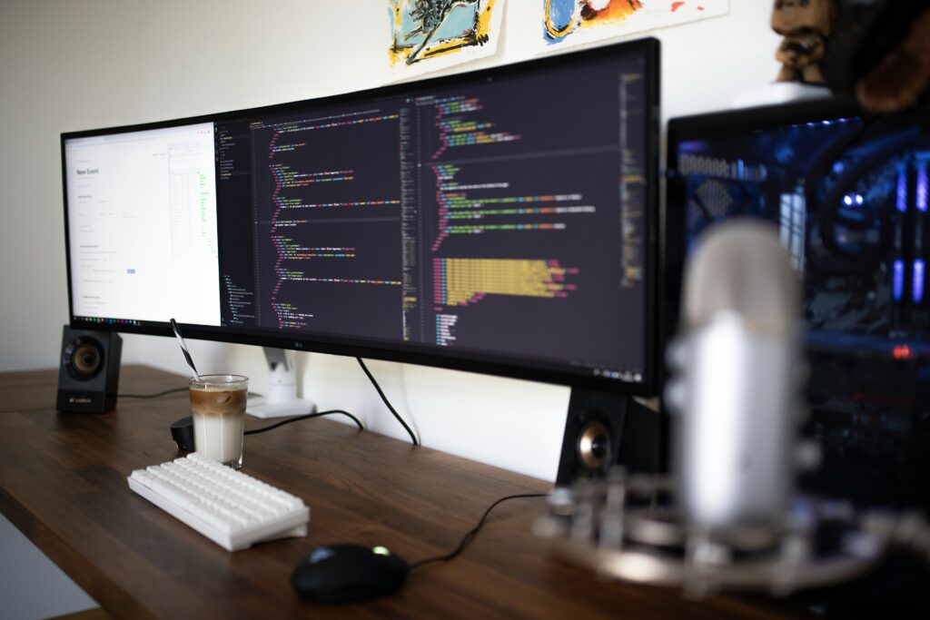 A modern developer's desk featuring an ultrawide monitor with lines of code