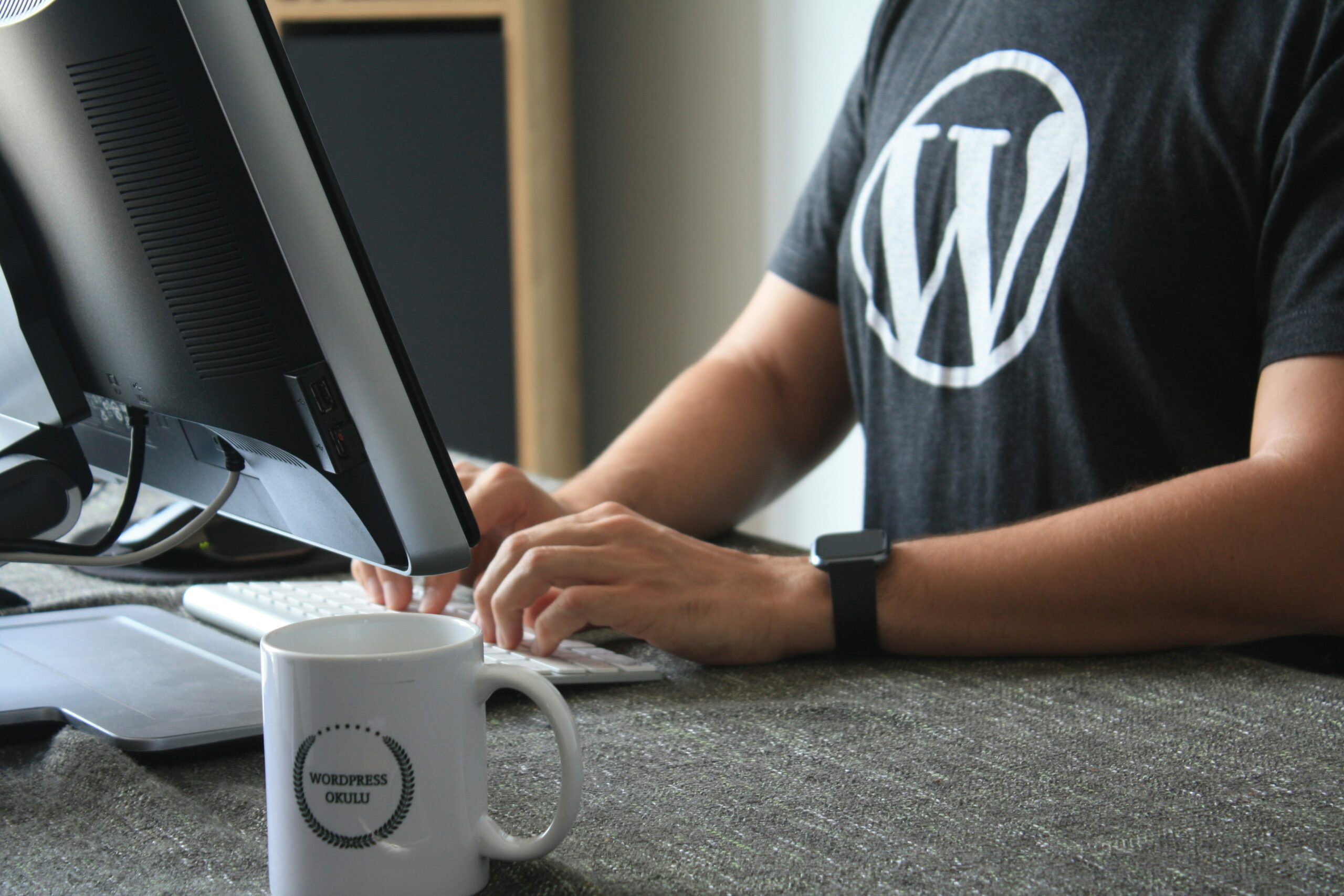 A developer wearing a WordPress t-shirt while working on a computer