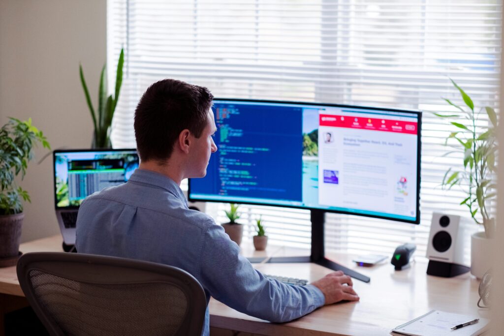 Web developer working at a desk with dual monitors coding and designing a Drupal website