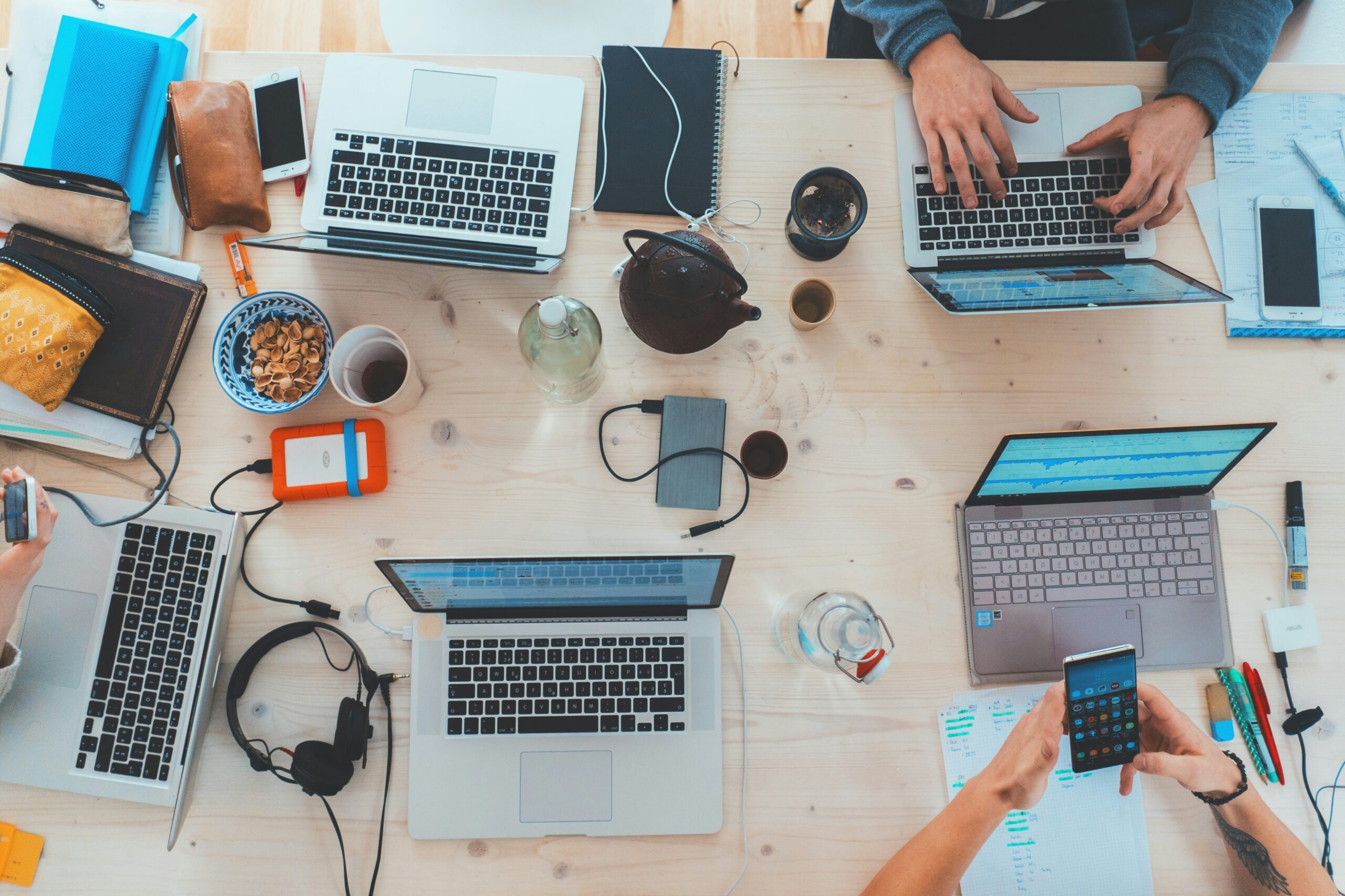 Top view of a collaborative workspace with laptops, smartphones, and tech gadgets, where a group of people are working on app or software development