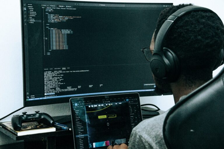 A Joomla developer wearing headphones and writing code on a computer