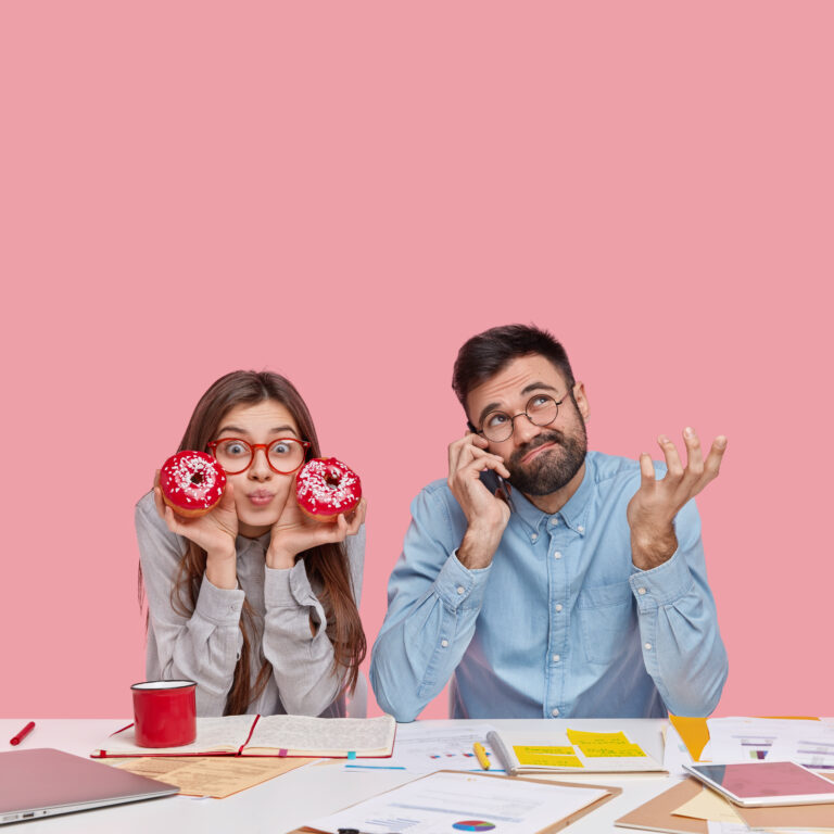 oung woman playfully holding donuts over her eyes while a man beside her talks on the phone with a confused expression, illustrating meme-style marketing humor