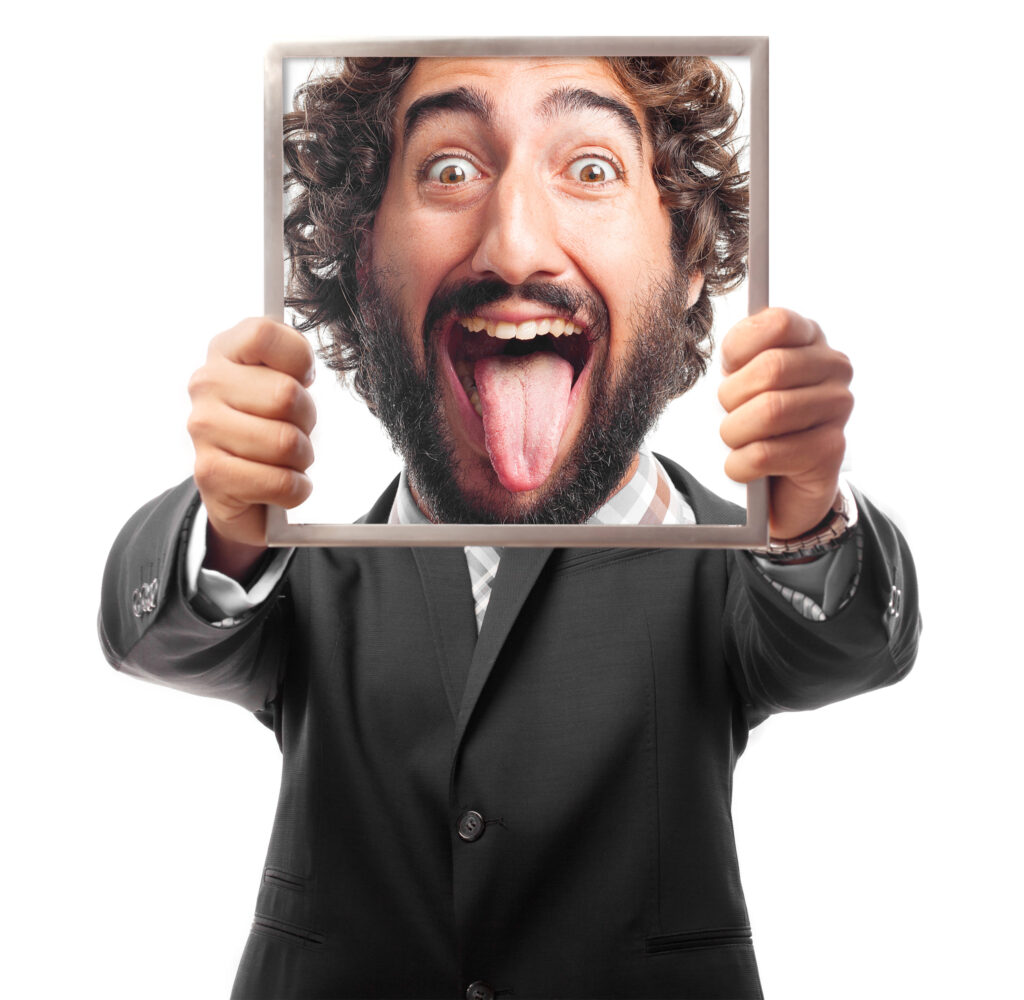 Man in a suit holding a picture frame with a funny face sticking out his tongue, representing playful and creative meme marketing content